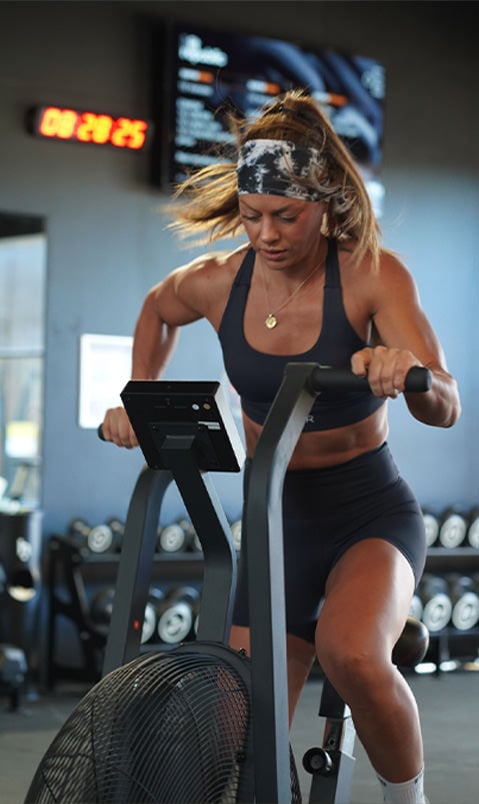 Brand ambassador on a workout bike, wearing a black sports bra and black shorts