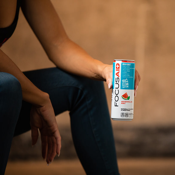 A woman holding a can of FOCUSAID Watermelon Mint.