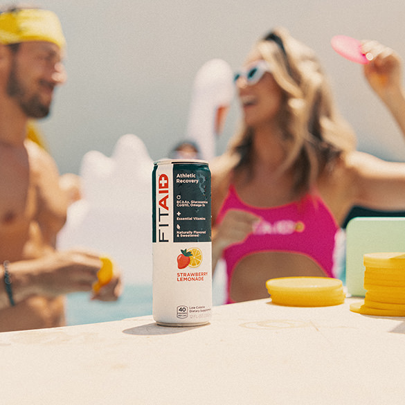 Athletic man and woman are chatting accompanied by a can of FITAID Strawberry Lemonade.