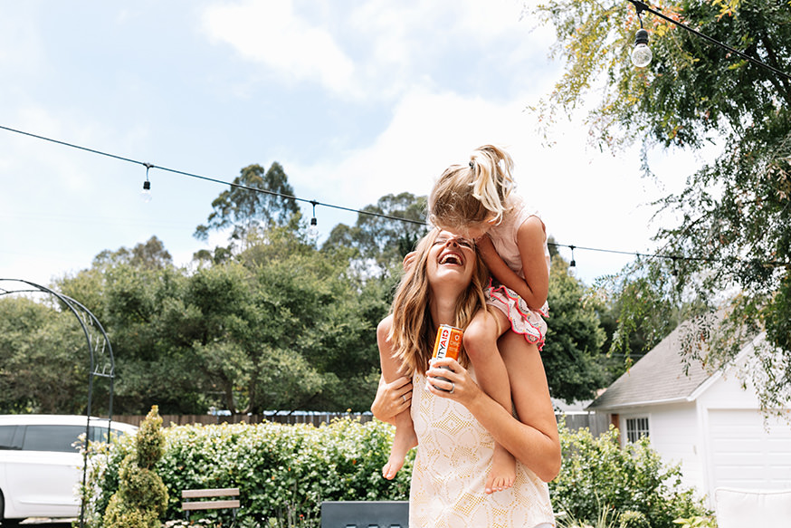 A mother carrying her daughter while holding a IMMUNITYAID can.