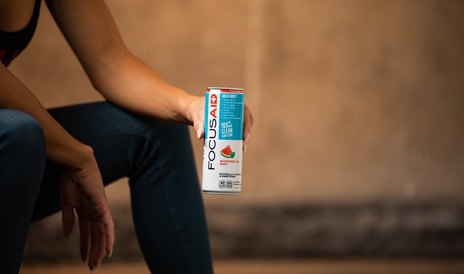 A woman holding a can of FOCUSAID Watermelon Mint.