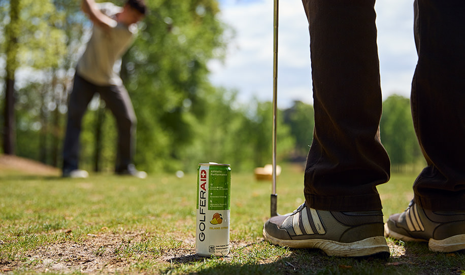 A golfer standing beside a can of GOLFERAID.