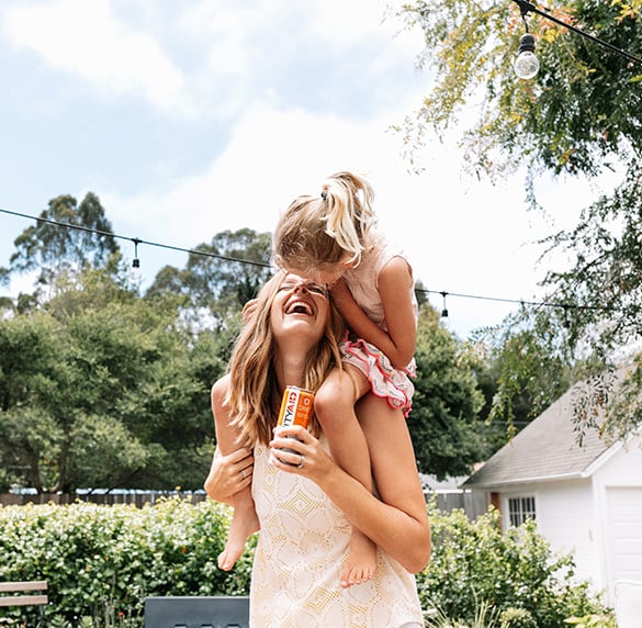 A mother carrying her daughter while holding a IMMUNITYAID can.