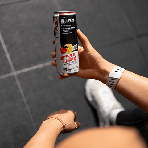 Athletic man and woman are chatting accompanied by a can of FITAID Strawberry Lemonade.