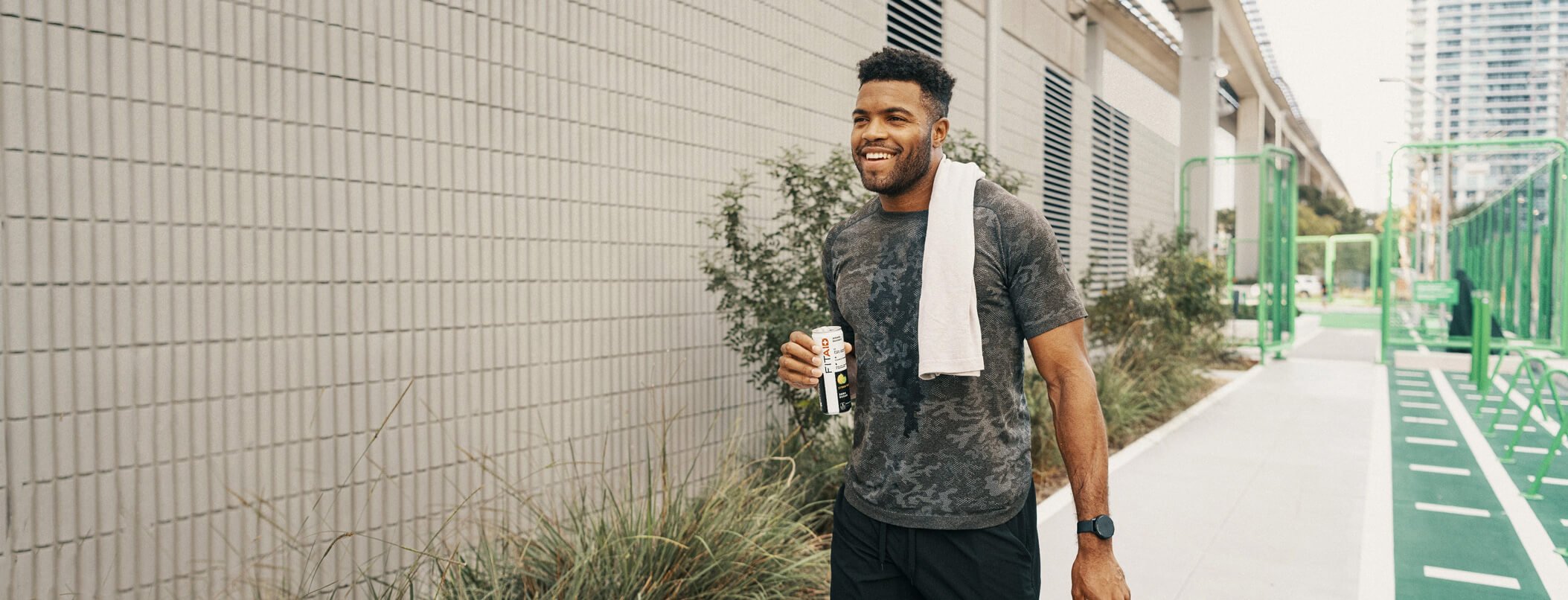 A man with a towel around his neck is walking down a sidewalk