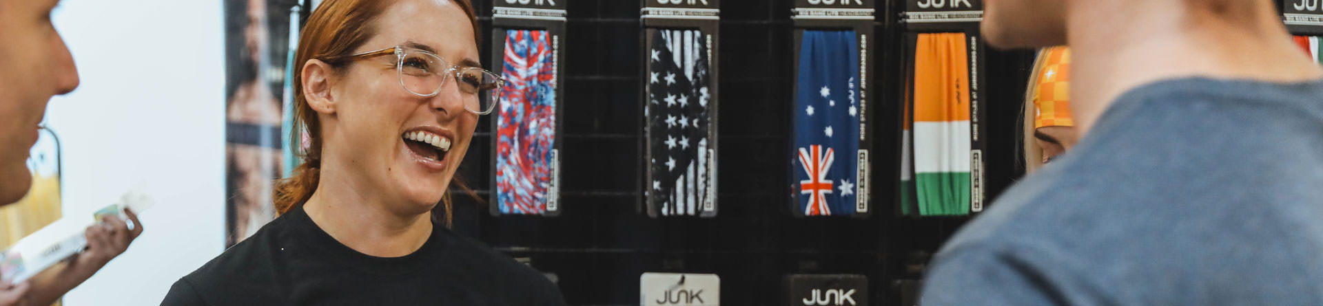 C ** ** JUK JUK. A woman is laughing in front of a display of junk socks